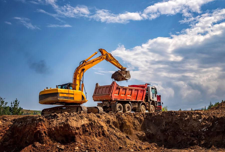 An excavator loading excavated soil onto a truck